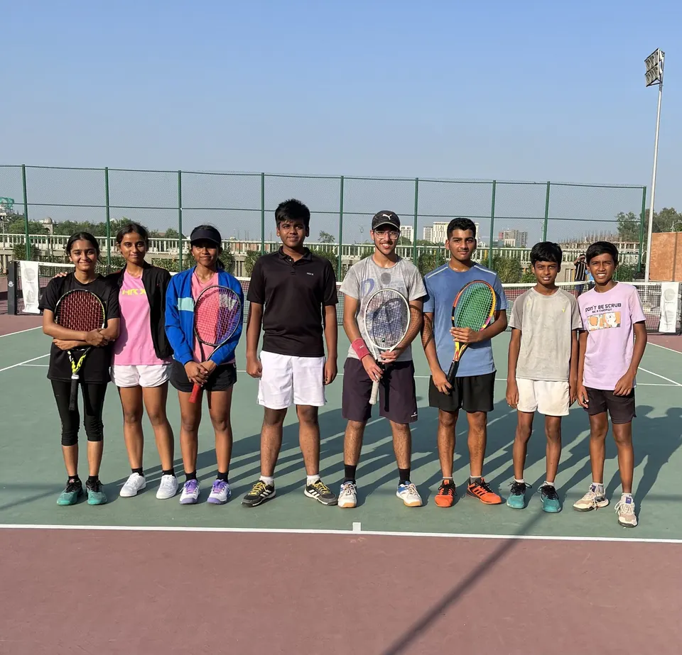 Players lined up on a hard court with floodlight towers behind